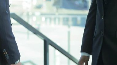 Dinamik bir sahnede, takım elbiseli iki iş adamı sıkı bir tokalaşma içinde, ortaklık ve işbirliğini sembolize ediyor. Onların kendine güvenen gülümsemeleri ve profesyonel kıyafetleri başarılı bir iş atmosferini yansıtıyor, yeni fırsatlar yaratıyor ve