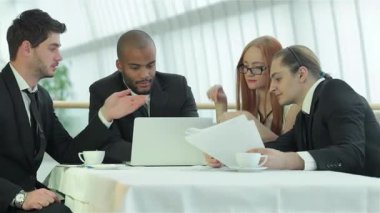 Aralarında iki erkek ve iki kadının da yer aldığı dört kendinden emin profesyonelden oluşan bir grup, parlak bir ofisteki gösterişli bir masanın etrafında hevesle işbirliği yapıyor. Gülüşleri ve hareketleriyle, stratejileri tartışıp paylaştıkları verimli bir atmosferi yansıtıyorlar.