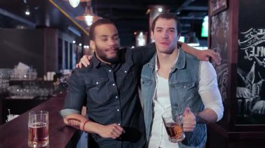 Birinde sakallı, diğerinde kot yelekli iki eski arkadaşın barda keyifli bir anın tadını çıkarması gibi hayat dolu bir sahne başlıyor. Sohbetin vızıltısı ve bira bardaklarının şıngırtısıyla çevrelenmiş bir şekilde, yoldaşlığı kutlarken aynı zamanda tezahürat yapıyorlar.