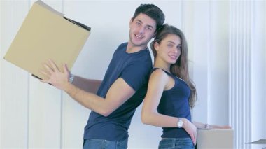 Neşeli bir çift sırt sırta durur, her biri bir karton kutu taşır, yeni, boş dairelerinde heyecan yayarlar. Çıplak duvarlar ve rahat bir kanepeyle çevrili gülümsemeleri birlikte yeni bir sayfa açmanın heyecanını yansıtıyor.