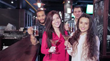 Neşeli bir grup genç arkadaş kadehlerini hareketli bir barda kaldırarak neşe ve dostluk saçıyor. En sevdikleri futbol takımı için tezahürat yaparken, coşkulu atmosfer kahkaha ve heyecanla dolu. Unutulmaz bir ortam yaratıyorlar.