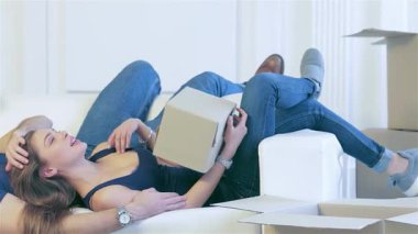 Neşeli bir çift, yeni evlerindeki paketsiz kutularla çevrili, sıcak ve sevgi dolu, rahat beyaz bir kanepede yatıyor. Sahne, yeni bir sayfa açmanın heyecanını somutlaştıran hassas bir anı paylaşırlarken onların neşeli sevgisini yakalar.