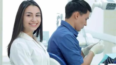 Parlak bir diş kliniğinde, yetenekli bir diş hekimi hastasının dişlerini tedavi etmeye odaklanırken, neşeli bir asistan da olumlu bir şekilde ışıldıyor. Bu ilgi çekici sahne, diş bakımında takım çalışmasının özünü yakalar, bağlılığını gösterir.