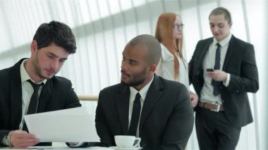 Zarif, modern bir ofiste, iki kendine güvenen işadamı, önemli belgeleri, kararlılık ve işbirliğini yansıtan ifadelerini tartışmakla derinden meşguller. Atmosfer, işlerini yaparken profesyonellikle doludur.