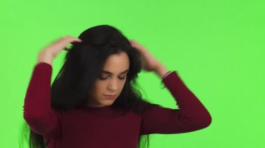 Uzun siyah saçlı güzel bir genç kadın, parlak yeşil bir arka plana karşı endişelerini düşünürken elini alnında dinlendirirken gözle görülür şekilde sıkıntılı. Bu dokunaklı görüntü kaygı ve duygusal karmaşanın özünü yakalıyor.