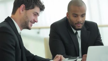 İki gülümseyen iş adamı, doğal ışıkla çevrili şık bir konferans masasında canlı bir tartışmaya girişirler. Onların özgüvenli ifadeleri ve profesyonel kıyafetleri başarılı bir ortaklığı, takım çalışmasını ve kurumsal yenilikleri yansıtıyor.