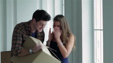 Birbirine aşık genç bir çift, yeni evlerinde paketlenmemiş karton kutularla çevrili bir kutuyu tutarken güneşli bir pencereden dışarı bakıyorlar. İfadeleri mutluluk ve heyecan saçıyor, yeni bir hayata başlamanın heyecanını simgeliyor.