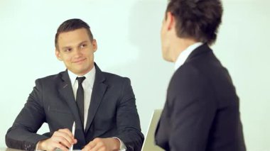 Gülümseyen iki genç işadamı, modern bir ofis ortamında dostluk ve profesyonellik sergileyen bir iş planını animasyon olarak tartışıyor. Kendine güvenen ifadeleri ve keskin giysileri, işbirliği ve yeniliğin dinamik atmosferini yansıtıyor.