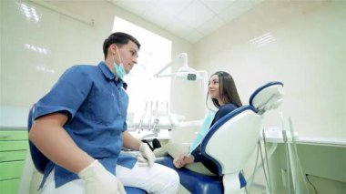 Parlak bir diş kliniğinde, genç, kendine güvenen bir dişçi, kameraya baş parmağını göstermek için dönen bir hastayla ilişki kurar. Bu canlı an, dostça diş bakımının özünü yakalıyor ve sağlık ve...