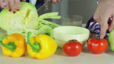 Lezzetli bir akşam yemeği için renkli biberler ve olgun domatesler de dahil olmak üzere taze sebzeleri neşeyle doğrayan genç, gülümseyen bir mutfak sahnesinin yakın çekimi. Atmosfer kahkaha ve arkadaşlıkla dolu.