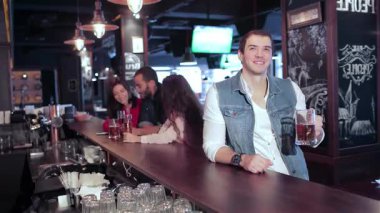 Canlı bir bar sahnesi, en sevdikleri futbol takımı için kutlama ve tezahürat yapan arkadaşlarıyla çevrili soğuk bir bira tutan genç bir adamı yakalıyor. Atmosfer kahkahalarla, arkadaşlıkla ve herkesin eğlendiği gibi bardakların tıkırtısıyla dolu.