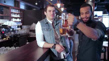 İki neşeli arkadaşın, canlı bir atmosferle çevrili buzlu bira bardaklarıyla kadeh kaldırırken barda canlı bir sahne beliriyor. Arkadaşlık, en sevdikleri futbol takımı için tezahürat yaparken, dostluk ve kutlama ruhunu somutlaştırır.