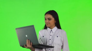 Canlı, beyaz bir gömlek giymiş genç bir iş kadını, parlak bir kromakey arka planda bilgisayarında neşeyle etkileşime geçiyor. Animasyon ifadeleri ve jestleri, modern çağın özünü somutlaştıran coşku ve profesyonelliği ifade ediyor.