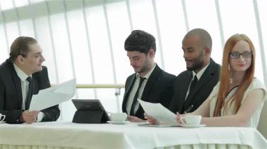 Sivri giyinmiş dört genç profesyonelden oluşan canlı bir toplantı, zarif bir konferans masasının etrafında gülücükler ve fikirler paylaşıyor. Stratejileri tartışıp kutlama yaparken, parlak, modern ofis kurulumu işbirlikçi ruhlarını geliştiriyor.