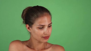 Göz kamaştırıcı genç bir kadının büyüleyici portresi. Doğal bir ışıltıyla, canlı yeşil bir arkaplana zarif bir şekilde poz veriyor. Çıplak cildi sağlık ve güzellik saçıyor, hayranlık uyandırıyor ve kadınlığın ve kendine güvenin özünü sergiliyor.