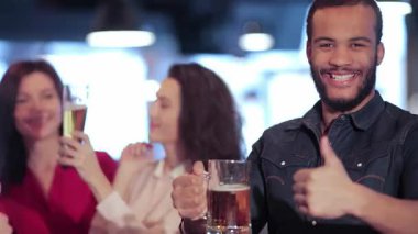 Neşeli bir sahne, gülümseyen Afrikalı bir çocuğun, kutlama için kadehlerini kaldıran iki neşeli kızla çevrili, gururla baş parmağını kaldırdığı bir barda başlıyor. Dostlar içkinin tadını çıkarırken, en sevdikleri için tezahürat yaparken ortam heyecan vericidir.