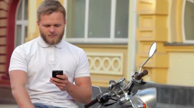 Süslü, bakımlı sakallı genç bir adam, akıllı telefonuna dalmış, gösterişli scooterına biner. Canlı kentsel zemin, özgürlük ve macera hissini artırıyor, izleyicileri şehirde sakin bir gezinti yapmaya davet ediyor.