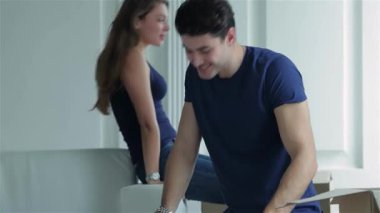 Parlak, boş bir dairede, sevecen bir çift, karton kaplar ve çıplak duvarlarla çevrili kutuları neşeyle açıyor. Kadın kanepede otururken, adam kutudan bir şeyler çıkarırken gülümsüyor, yeni çocukları için mutluluk ve heyecan saçıyor.