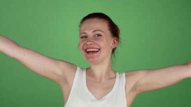 Canlı bir stüdyo çekimi, kızıl saçlı, neşeli bir şekilde gülümseyen ve canlı yeşil renkli bir arka plana karşı iki kez onay veren genç, ışıl ışıl bir kadını yakalar. Bulaşıcı neşesi ve coşkusu, başarı ruhunu somutlaştırıyor.