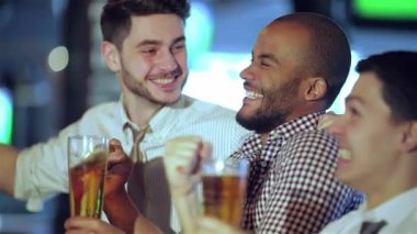 Üç neşeli arkadaş, beyaz bir adam, siyah bir adam ve İspanyol bir adam canlı bir barda bira bardaklarını kaldırıyor ve televizyonda heyecan verici bir futbol maçını kutluyorlar. Bulaşıcı kahkahaları ve tezahüratları heyecan verici bir atmosfer yaratıyor.