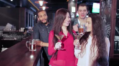 Genç erkek ve kadınların modaya uygun bir barda toplanıp kadehlerini kaldırmaları. En sevdikleri futbol takımı için coşkulu bir dekor ve bardakların tıkırtısıyla çevrelenmiş bir şekilde tezahürat yaparken atmosfer heyecanla titriyor.