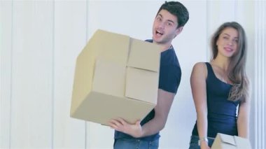 Çıplak duvarlar ve hareketli kaosla çevrili yeni yenilenmiş dairelerinde kutuları açarken neşe dolu bir çift. Paylaştıkları kahkaha ve şefkat, yeni hayatlarının başlangıcını sembolize eden sıcak bir atmosfer yaratıyor.