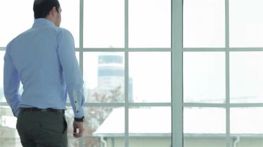 Kendine güvenen resmi gömlekli bir işadamı, karlı bir şehir manzarasını çerçeveleyen büyük bir pencerenin yanında saatine bakıyor. Bu canlı sahne tutku ve başarının özünü yansıtıyor. Modern çağında önemli bir buluşmaya hazırlanıyor.