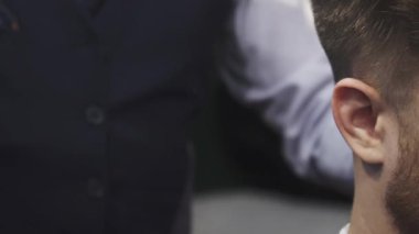 Odaklanmış bir yakın plan bir berber dükkanında genç bir adamı yakalar, yetenekli bir berber saçını ustalıkla kırpar. Atmosfer beklenti ve stil ile dolu, tımar sanatının göstergesi ve müşterilerin dönüşümü