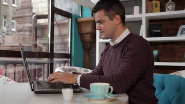 Rahat bir Kafkasyalı, rahat bir kafede işini düzgün bir dizüstü bilgisayarla bitirdikten sonra kollarını uzatıyor. Yanında bir fincan espresso ile sıcak ortam, üretkenlik ve konforun mükemmel bir karışımını yaratır.