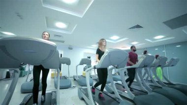 Hareketli bir grup sporcu spor salonunda enerjik bir koşu bandı egzersizi yapıyor ve spora olan bağlılıklarını sergiliyorlar. Canlı bir atmosferle, sahne genç erkek ve kadınların şık spor kıyafetlerinde kararlılıklarını yakalıyor,