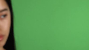 Büyüleyici bir kayma sahnesi, kusursuz derisi ve şık dudak halkası olan çarpıcı genç Asyalı bir kadını canlı yeşil renkli bir arka plana karşı güvenle poz vererek yakalar. Onun sakin ifadesi ve pürüzsüz yüz hatları bir güzellik hissi uyandırıyor.