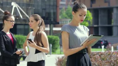 Canlı bir şehir ortamında, kendinden emin genç bir iş kadını, meşgul meslektaşlarıyla çevrili tabletinde dikkatle geziniyor. Sahne modern işbirliğinin özünü yakalıyor, profesyonel etkileşimlerin dinamik enerjisini gözler önüne seriyor.