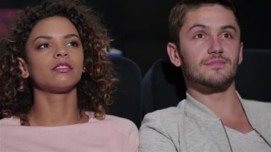 Çekici bir çift sıcak bir sinemada yan yana oturur, ekrandaki film karşısında büyülenirler. İfadeleri neşe ve heyecan saçıyor, tiyatronun sıcak atmosferiyle çevrili, arkadaşlar kahkahaları ve patlamış mısırları paylaşıyor, unutulmaz bir şekilde yaratıyorlar.