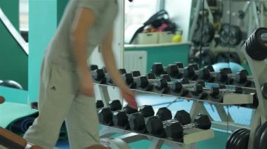 Kendini adamış bir fitness eğitmeni, genç bir adama karın egzersizinde rehberlik eder. Uygun form ve tekniği gösterir. Ağırlık ve egzersiz malzemeleriyle dolu canlı spor salonu, enerji ve motivasyon yayıyor, sağlığa bağlılığa ilham veriyor.