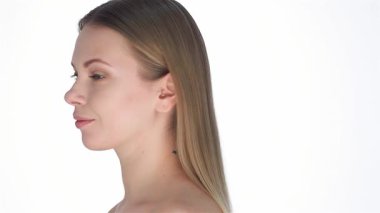 Işıl ışıl sarışın bir kadın zarifçe döner, kusursuz cildini gösterir ve saf beyaz bir arka plana karşı parlak bir gülümseme sergiler. Bu çarpıcı portre güzelliğin ve özgüvenin özünü yansıtıyor, onun gençlik parıltısını ve zarafetini vurguluyor.