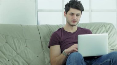 Neşeli genç bir kadın, erkek arkadaşına bilgisayarına odaklanırken dumanı tüten bir fincan kahveyle sürpriz yapar. Bu canlı sahne, arkadaşlığın ve aşkın neşesini yakalar, samimi bir kanepede neşeli bağlantılarını gösterir.