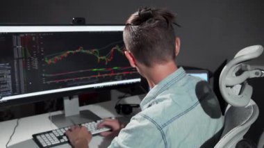 Genç bir erkek programcı, gece geç saatlerde ışıldayan ekranlarla çevrili işine dalmışken kameraya ışınlanıyor. Onun odaklanmış ifadesi ve monitördeki canlı veriler teknolojide ilham verici bir adanmışlık ve yenilik atmosferi yaratıyor.