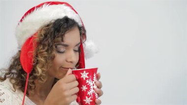 Noel Baba şapkası takan neşeli bir kız dumanı tüten bir bayram içeceğinin hoş kokusunu nazikçe içine çekiyor. Işıl ışıl gülüşü ve rahat süveteri Noel ve yeni yılı kutlamak için mükemmel bir ortam yaratıyor.