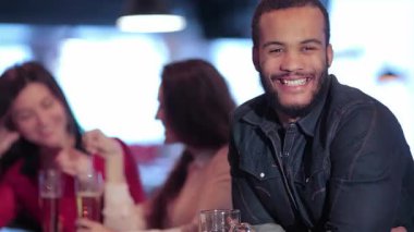 Neşeli bir Afrikalı adamın iki gülen kız tarafından çevrelendiği hareketli bir barda canlı bir sahne sergileniyor. Sıcak bira bardaklarıyla kadeh kaldırırken ortam heyecan verici. En sevdikleri futbol takımını coşkuyla kutluyorlar.