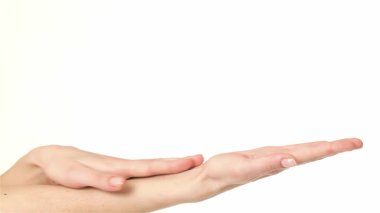 Genç beyaz bir kadının ellerini nazikçe okşayarak güzel parmaklarının zarafetini sergilediği yakın plan bir görüntü. Huzurlu atmosfer onun hassas dokunuşunu vurguluyor, gevşemesini ve el değmemiş beyaz bir arka plana karşı kendini korumasını vurguluyor.