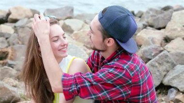 Neşeli bir üçlü genç arkadaş su kenarında neşeli bir anı paylaşıyor, alınları hafifçe birbirine dokunuyor ve gülümsüyor. Bu canlı sahne arkadaşlığın ve kaygısız yaz günlerinin özünü yakalıyor, sıcaklık ve bağlılık dolu.