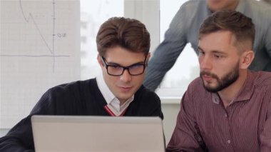 Aralarında gözlüklü şık esmer bir adam ve odaklanmış bir kadının da yer aldığı dört genç yaratıcı yönetici, bir dizüstü bilgisayarın etrafında toplanarak derin tartışmalara giriyorlar. Sarışın bir adam arkadan eğilip takım çalışmasının ve yeniliğin coşkulu atmosferine katkıda bulunuyor.