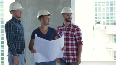 Sert şapkalı üç müteahhit hareketli bir inşaat sahasında gururla duruyor, dostluk ve kararlılık yayıyorlar. Merkezdeki Kafkasyalı adamın elinde, şık damalı gömlekler giyen iki işçi tarafından çevrelenmiş ayrıntılı bir plan var.