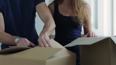 Neşeli bir çift, bir erkek ve bir kadın, neşeli bir şekilde, karton kaplarla çevrili, boş dairelerinde kutularını açıyorlar. Gülümsemeleri, hayatlarının bu yeni bölümüne adım atarken heyecan saçıyor. Çıplak bir boşluğa dönüşüyorlar.