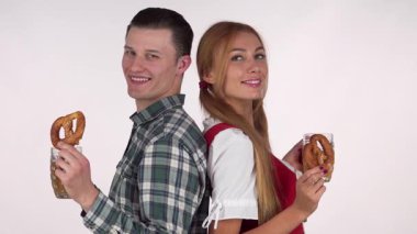 Geleneksel Dirndl giymiş çekici bir Bavyeralı kadın ve yakışıklı erkek arkadaşı köpüklü biraların ve lezzetli krakerlerin tadını çıkarıyorlar. Oktoberfest 'in neşeli ruhunu somutlaştırıyorlar. Sırt sırta vererek, aşkı ve geleneği kutluyorlar, canlı bir atmosfer yaratıyorlar.