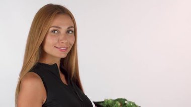 Uzun, dalgalı saçları olan neşeli bir kadın parlak siyah bir kasede taze salatanın enfes kokusunu içine çekiyor. Bu görüntü sağlıklı yaşamanın özünü yansıtıyor, onun ışıl ışıl gülüşünü ve besleyici yeme hevesini sergiliyor.