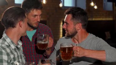 Bir grup yakışıklı adam, canlı bir bar ortamında neşeyle soğuk bira bardaklarını kaldırıyor. Kırsal tuğla duvarlar ve yumuşak ışıklıklarla vurgulanan ılık ortam, yoldaşlığın ve kutlamaların neşeli atmosferini güçlendiriyor.