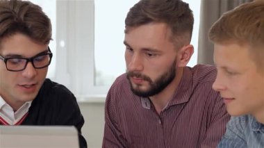 Şık beyaz bluzlu şık bir esmer kadın modern bir ofis masasında üç adama yaklaşır ve ilgi çekici bir sohbet başlatır. Sakallı bir adamla gözlüklü bir adam arasında dinamik bir değiş tokuş yaratırken atmosfer çok canlı.