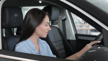 Siyah saçlı güzel genç bir kadın arabanın camından sarkıyor, neşe ve merak saçıyor. Büyüleyici gülümsemesi ve rahat tavırları izleyicileri keşif ve macera anını paylaşmaya davet ediyor.