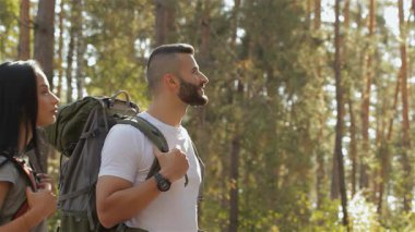 Sakallı bir erkek yürüyüşçü elini şevkle yukarı kaldırıyor ve güzel esmer kız arkadaşıyla hayranlık uyandırıcı bir manzara paylaşıyor. Çiftler güneşten sırılsıklam olmuş ormanda duraklarlar. Etrafı ağaçlarla çevrilidir. Macera ruhunu somutlaştırırlar.